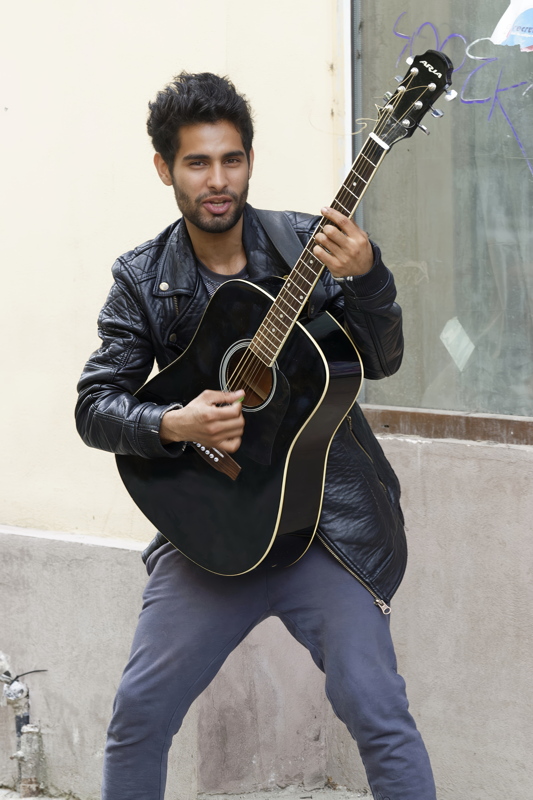 A musician playing an Aria AWN-15 acoustic guitar in a sleek black finish